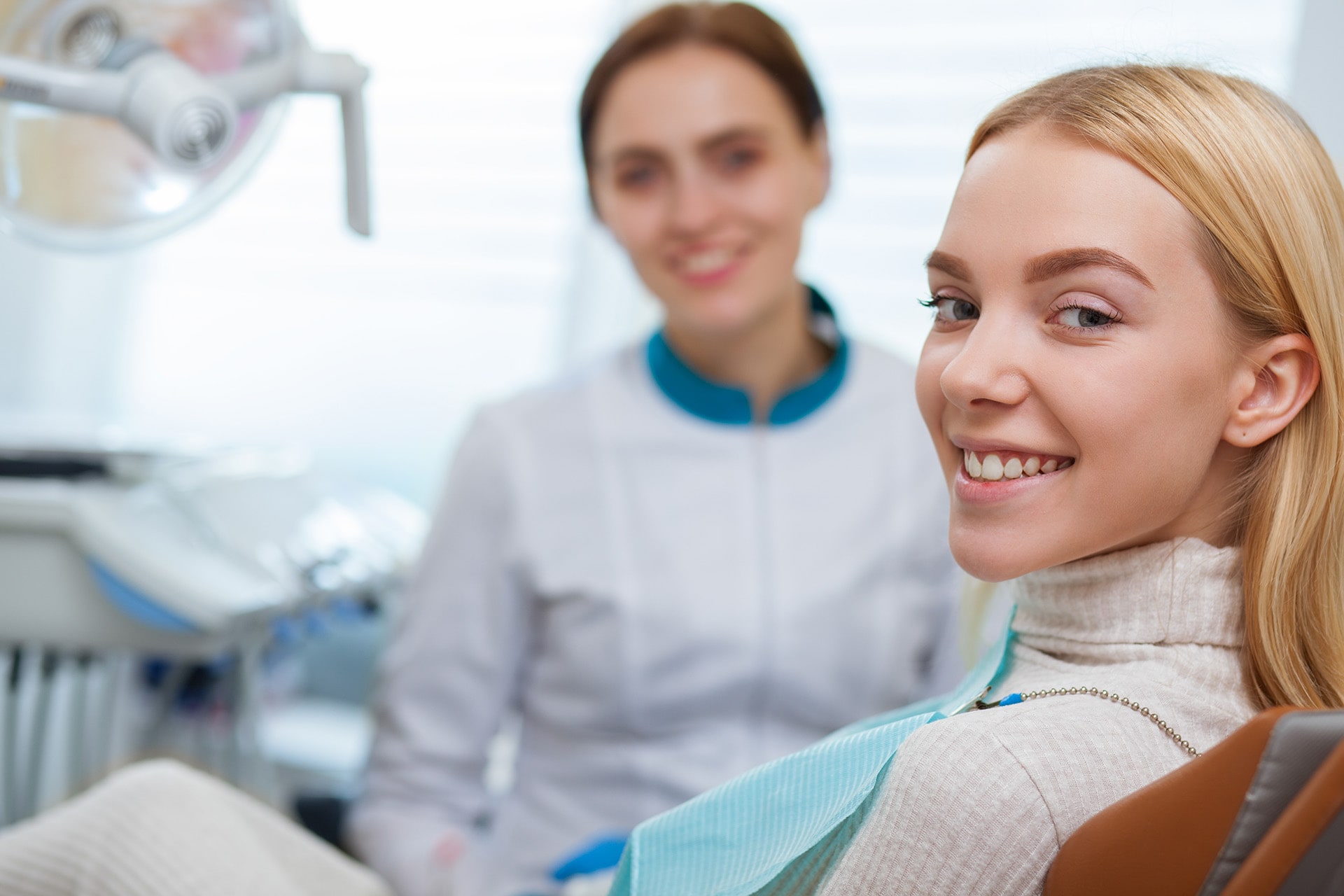 Woman smiling happily after receiving emergency dental care at a dental clinic, showcasing improved oral health.