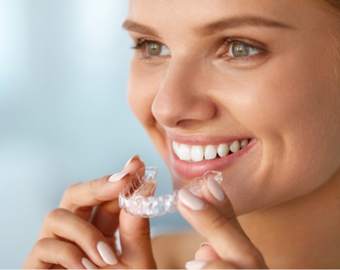 Woman wearing clear aligners for teeth straightening as part of orthodontic treatment.